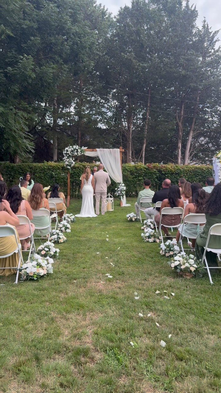 Wedding Themes 2026: 12 Ideas You Will Actually Want to Steal 3 A wedding ceremony held in a grassy backyard with a wooden floral arch and seated guests.