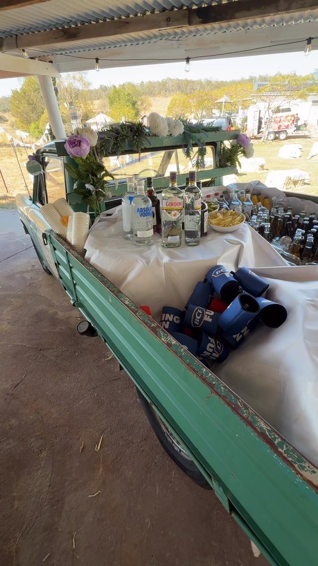 Wedding Themes 2026: 12 Ideas You Will Actually Want to Steal 6 A green vintage truck bed converted into a self-serve bar with liquor bottles and drinks.