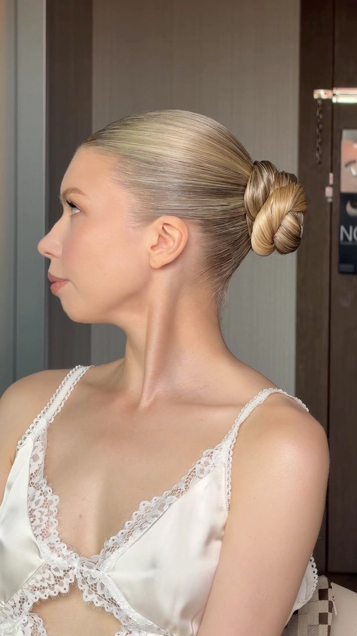 27 Bridesmaid Wedding Updo Hairstyles from Buns to Braids 11 Woman with blonde hair in a smooth, high ballerina bun wearing white lace.