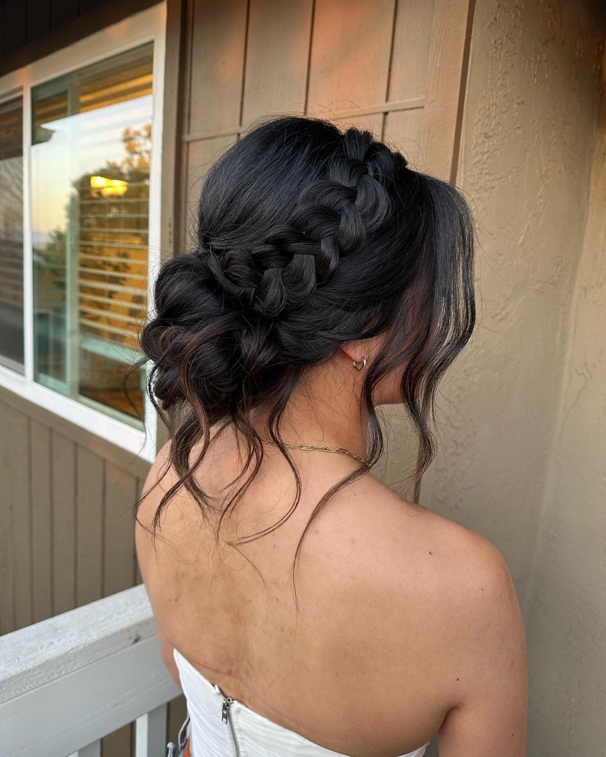 27 Bridesmaid Wedding Updo Hairstyles from Buns to Braids 12 Woman with dark hair in a boho braided bun and white strapless dress.