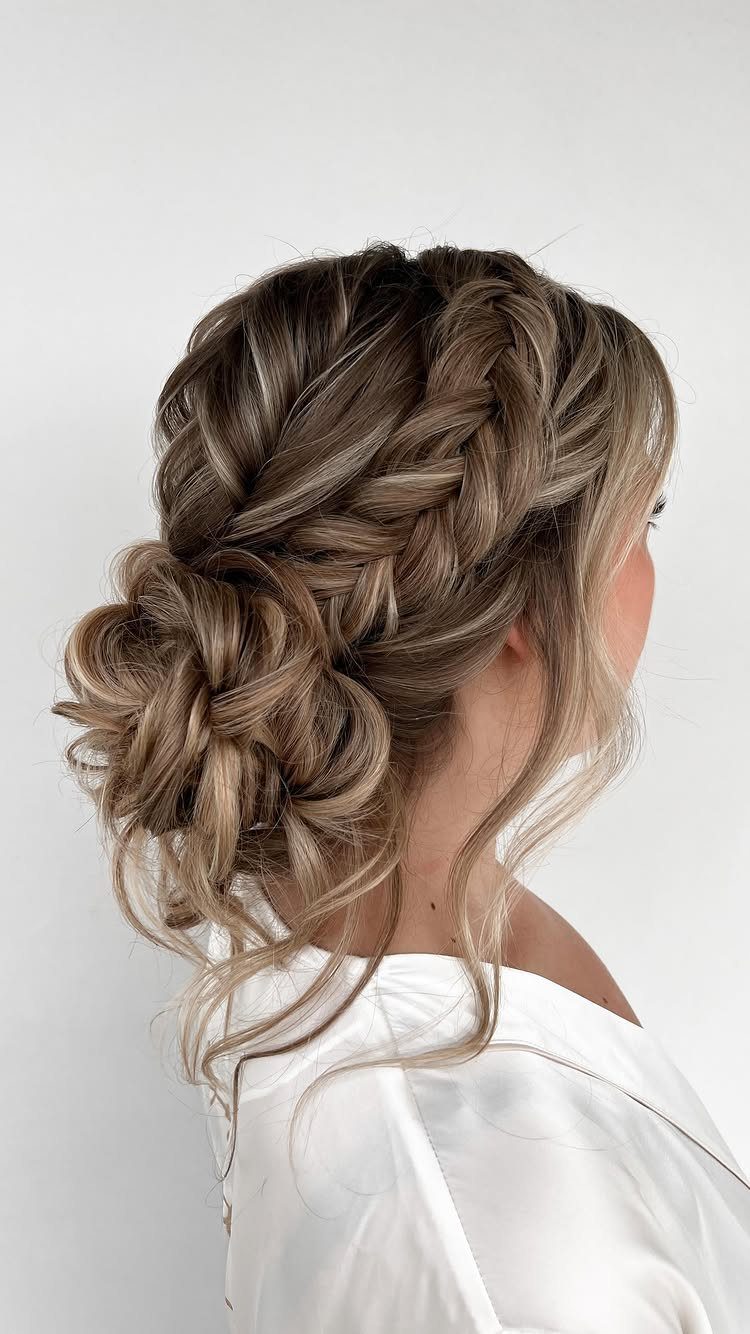 27 Bridesmaid Wedding Updo Hairstyles from Buns to Braids 26 Braided blonde updo with a low textured bun on a woman in white.
