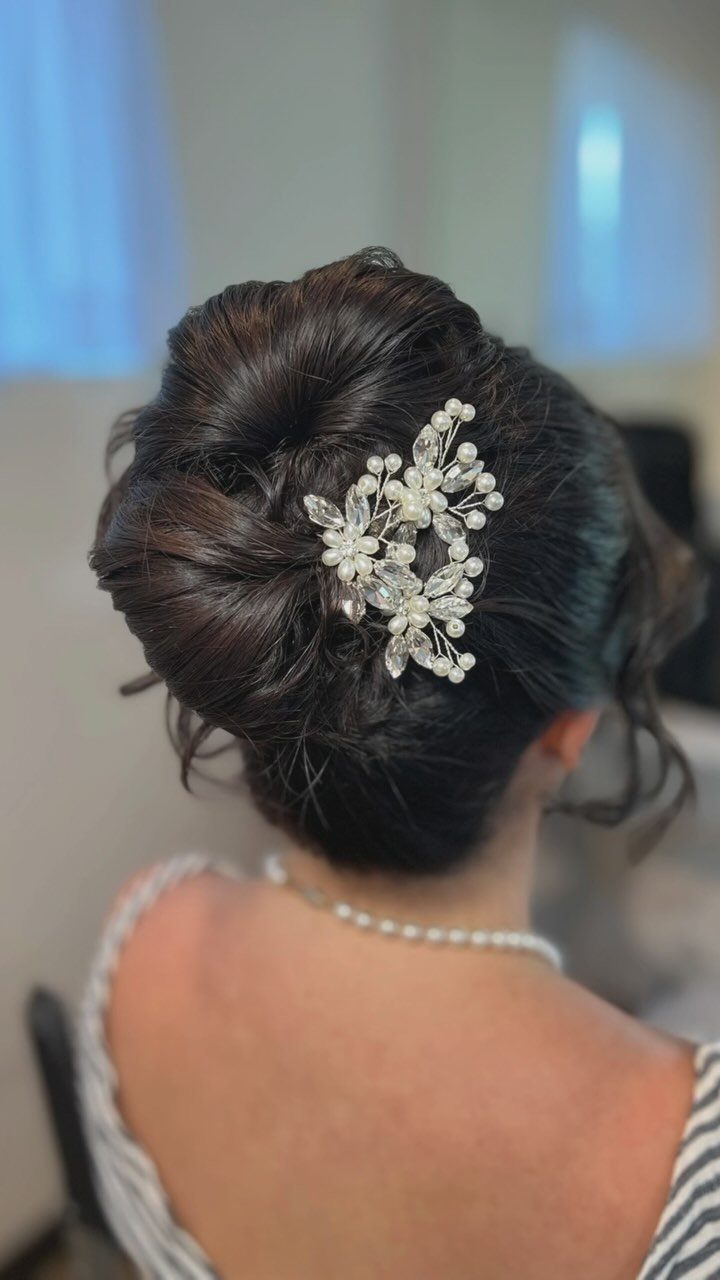 27 Bridesmaid Wedding Updo Hairstyles from Buns to Braids 16 Dark brown voluminous updo with a white pearl and crystal floral hair accessory.