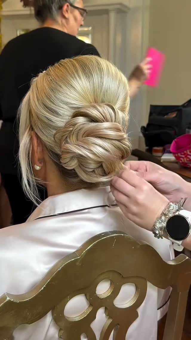 Wedding Updo Low Bun: How to Style 17 Beautiful Ideas 8 Blonde hair styled in a low sculpted bun being adjusted by a stylist.