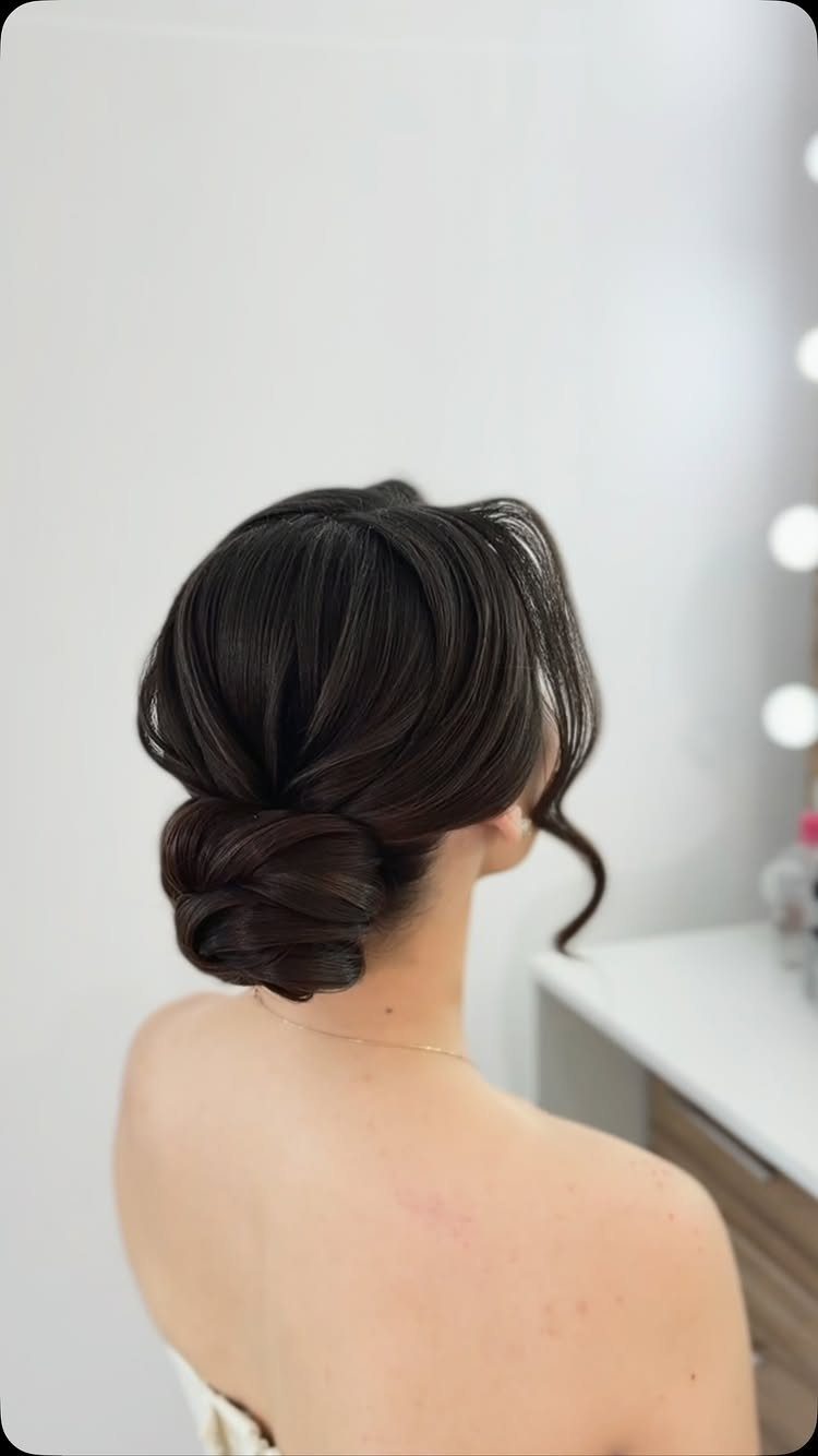 Wedding Updo Low Bun: How to Style 17 Beautiful Ideas 7 Dark brown hair styled in a side-part low bun with a face-framing curl.