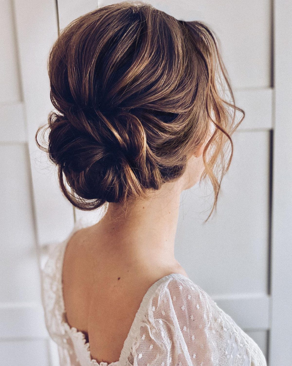 Wedding Updo Low Bun: How to Style 17 Beautiful Ideas 15 Brown hair styled in a twisted low bun with loose face-framing curls.