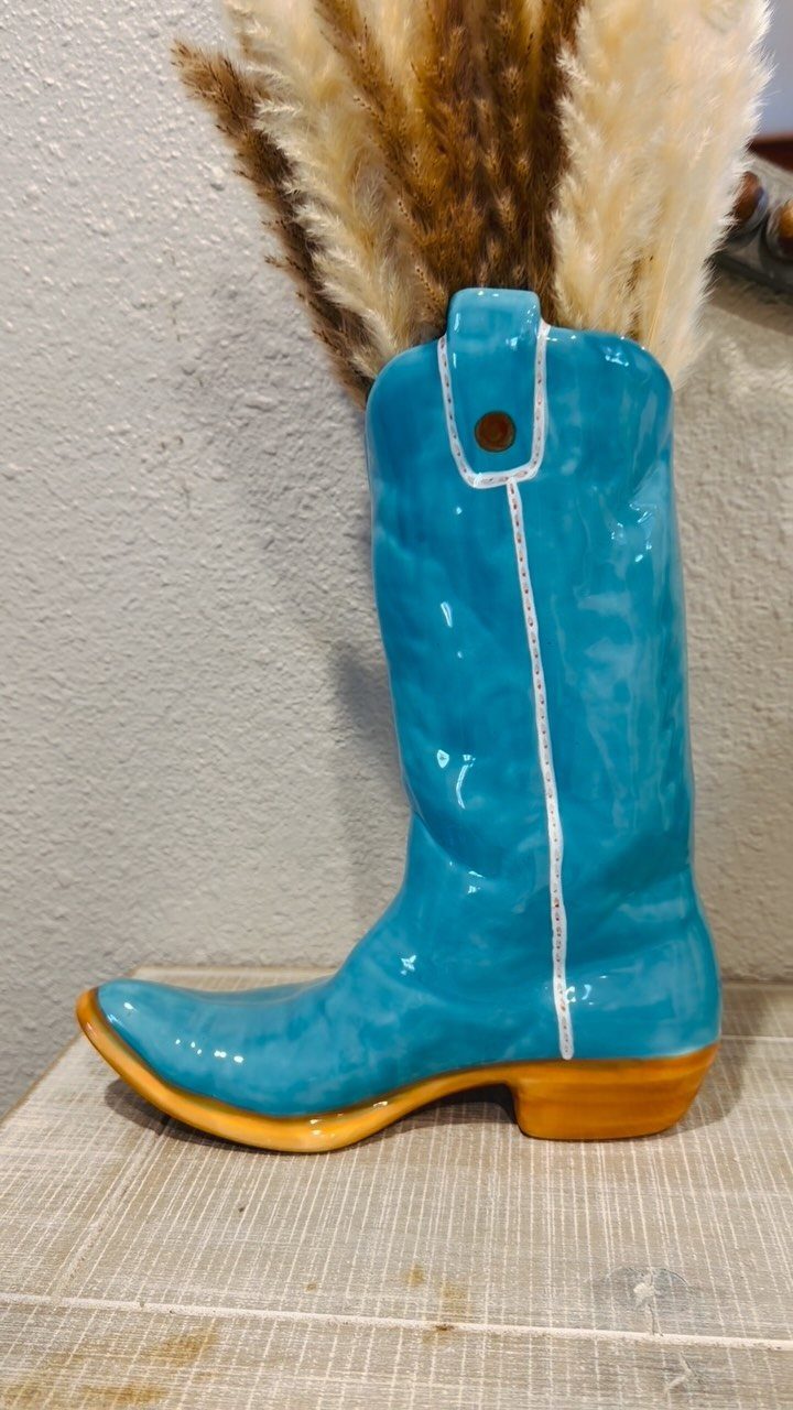 What Are the Best Western Themed Wedding Ideas? 37 Here 16 Blue ceramic cowboy boot vase filled with dried pampas grass on white wood.