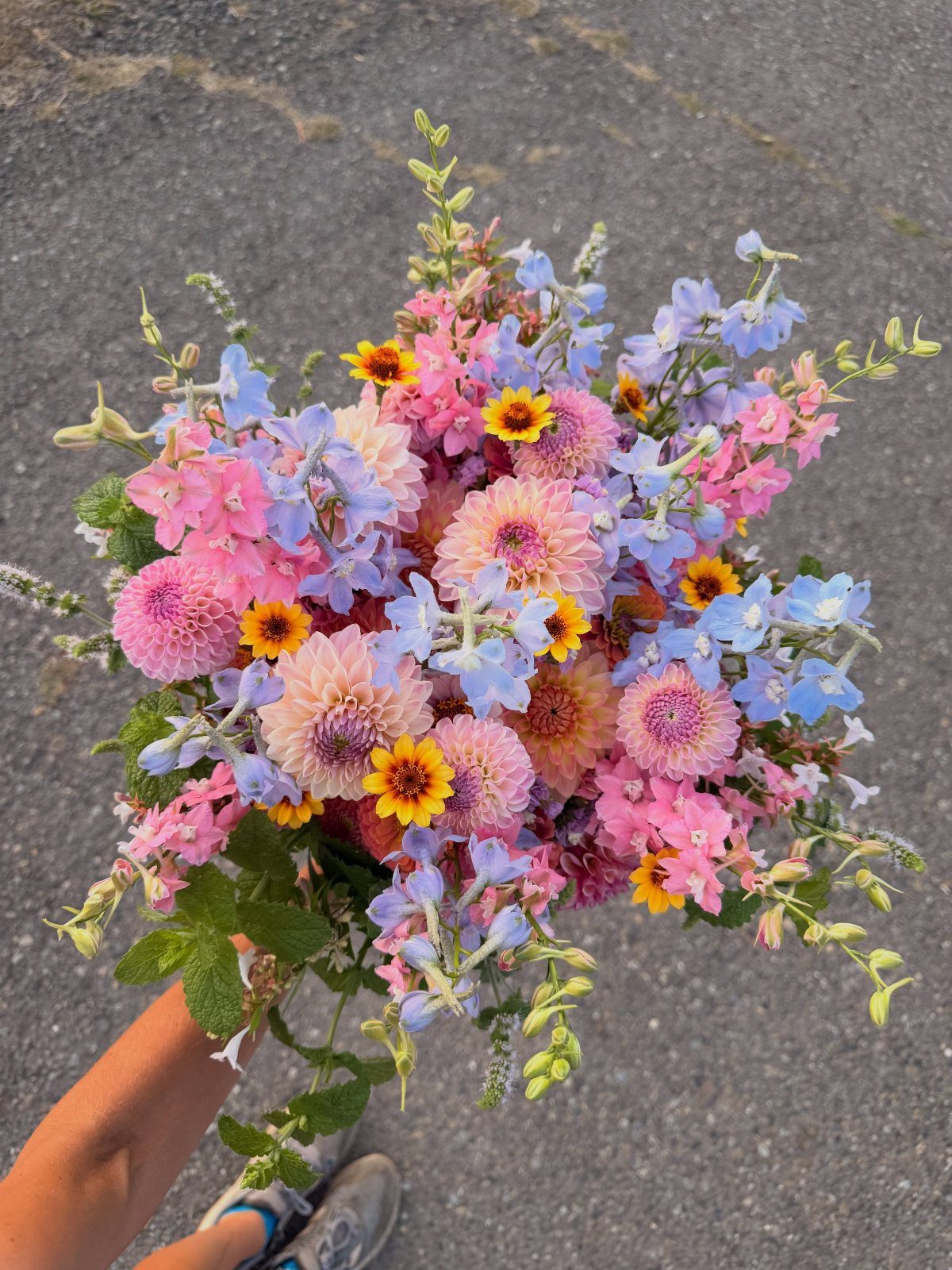 What Are the Best Western Themed Wedding Ideas? 37 Here 8 Colorful bridal bouquet with pink, blue, and yellow flowers held against asphalt.