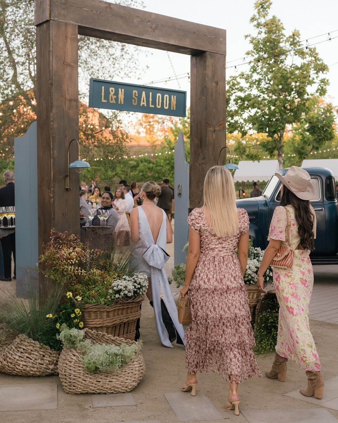 What Are the Best Western Themed Wedding Ideas? 37 Here 28 Women in dresses walking toward a rustic wooden saloon entrance at an outdoor event