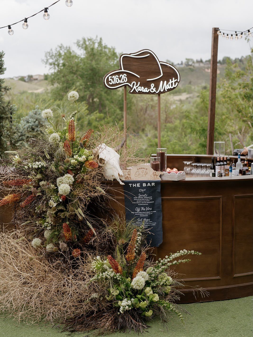 What Are the Best Western Themed Wedding Ideas? 37 Here 32 Rustic wooden wedding bar with cowboy hat sign and wild floral arrangements outdoors