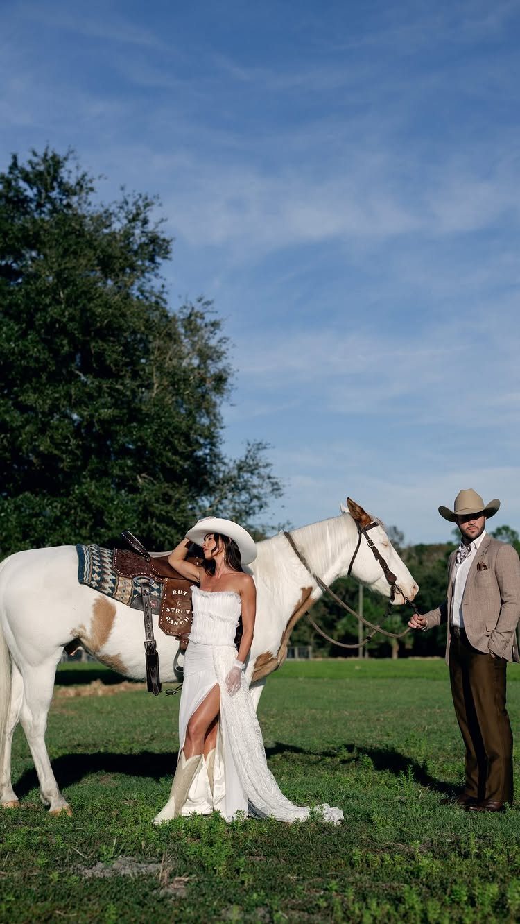 What Are the Best Western Themed Wedding Ideas? 37 Here 9 Bride in white wedding dress and cowboy hat standing with groom and horse.