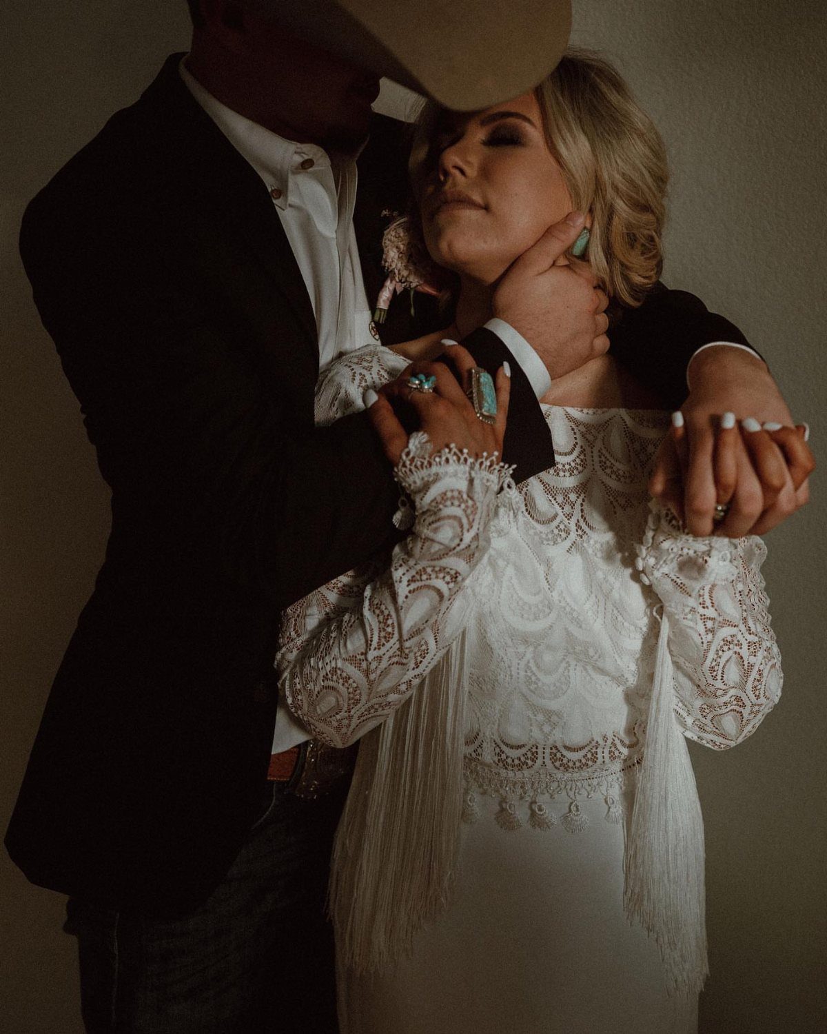 Couple in western wedding attire with woman wearing a fringed lace dress.