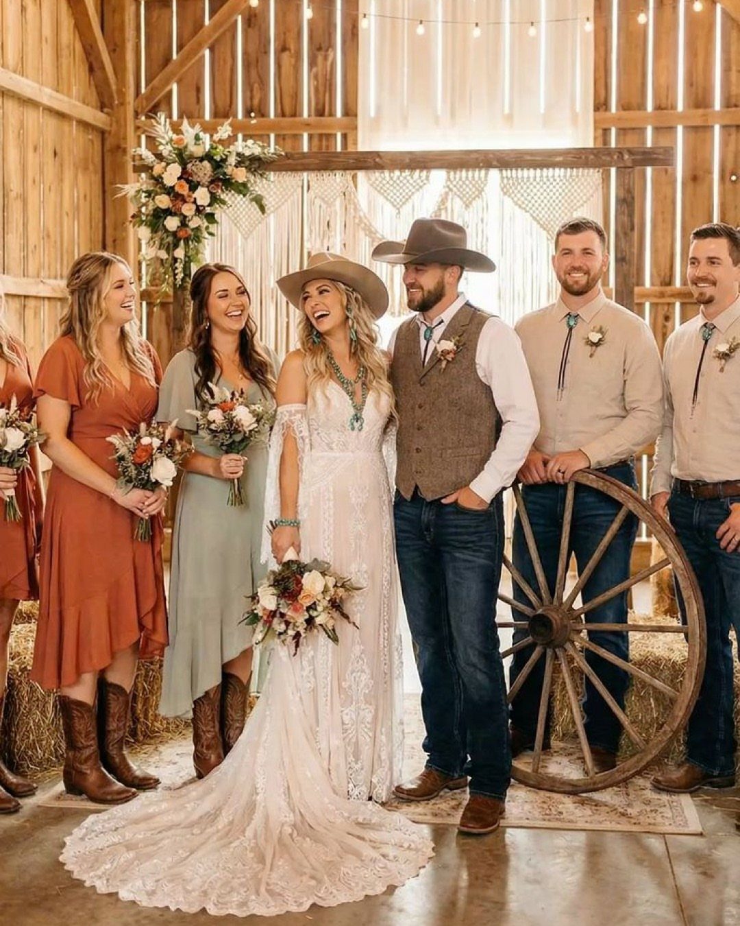 Wedding couple and party posing in a rustic barn with cowboy hats and boots.