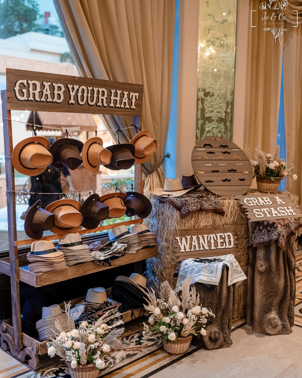 Cowboy hat display with rustic wooden signs and hay bales for a western party.