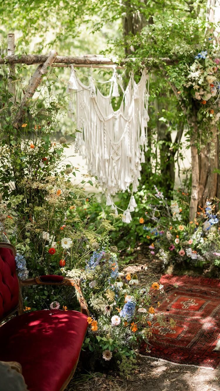 Whimsical Wildflower Wedding: 7 Decor Ideas That Feel Grown, Not Styled 2 Wildflowers and macrame decor surround a red velvet chair and rug under a wooden archway.