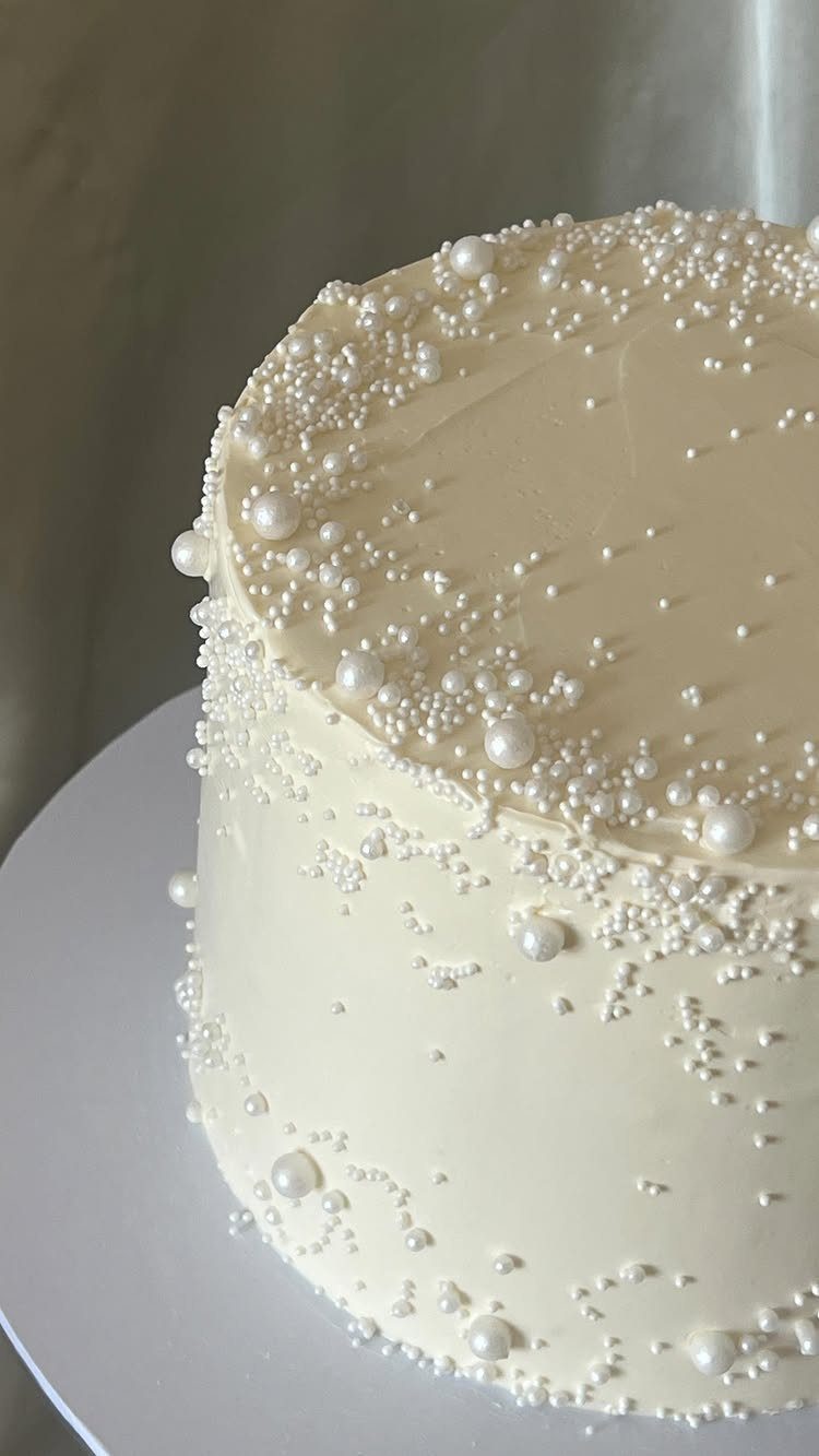 9 White Buttercream Cake Ideas That Look Bakery-Worthy at Home 7 White buttercream cake decorated with various sizes of white edible sugar pearls on a white stand.