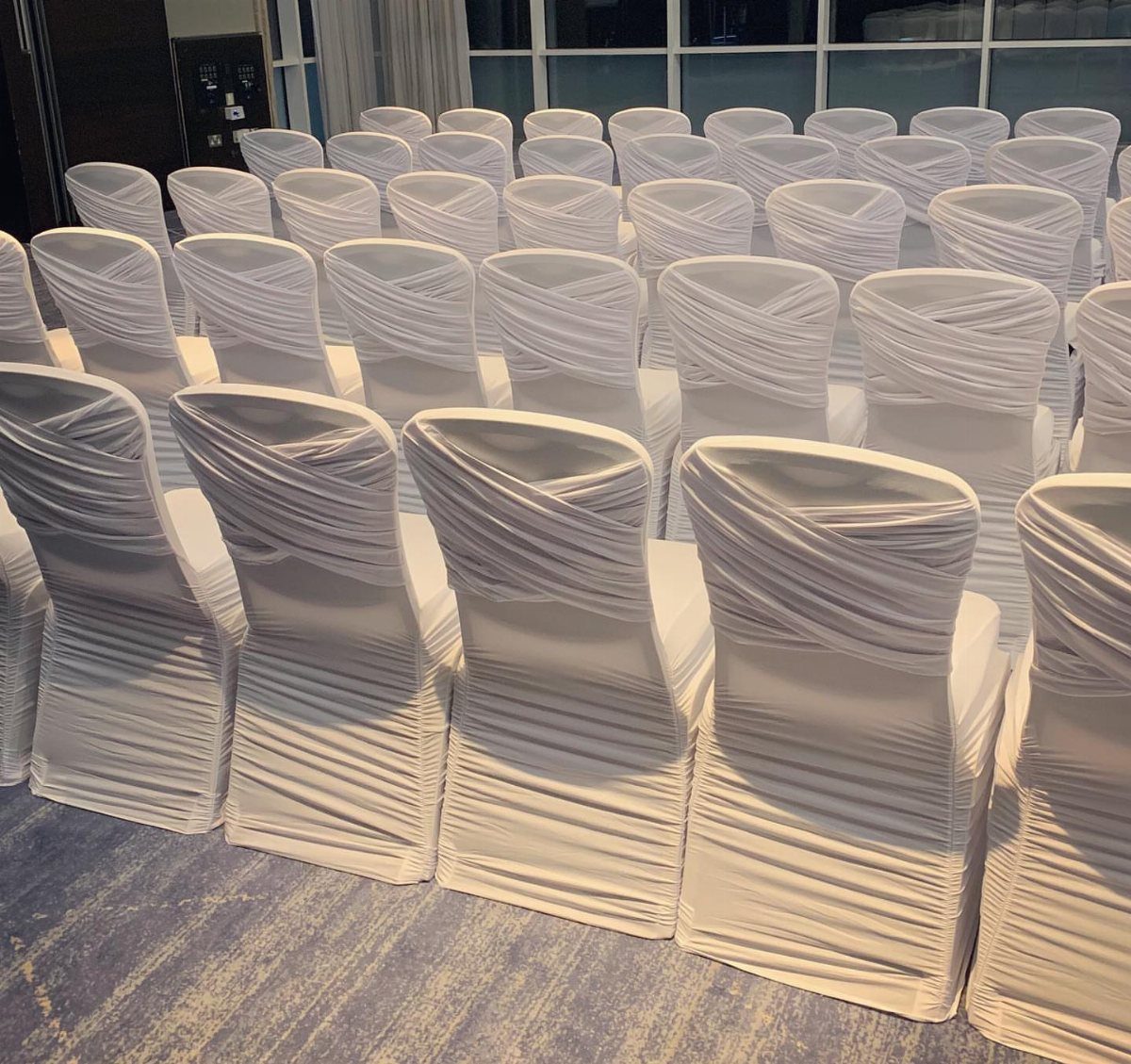 White Wedding Ideas: 23 Elegant Details for Your Big Day 22 White ceremony chairs draped in pleated white fabric arranged in neat rows.