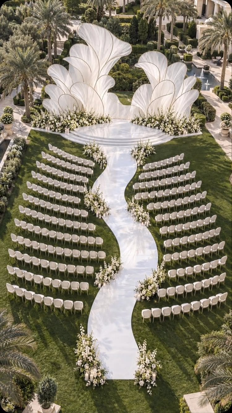White Wedding Ideas: 23 Elegant Details for Your Big Day 17 Curved mirrored white aisle runner with white chairs and floral arrangements on green grass.