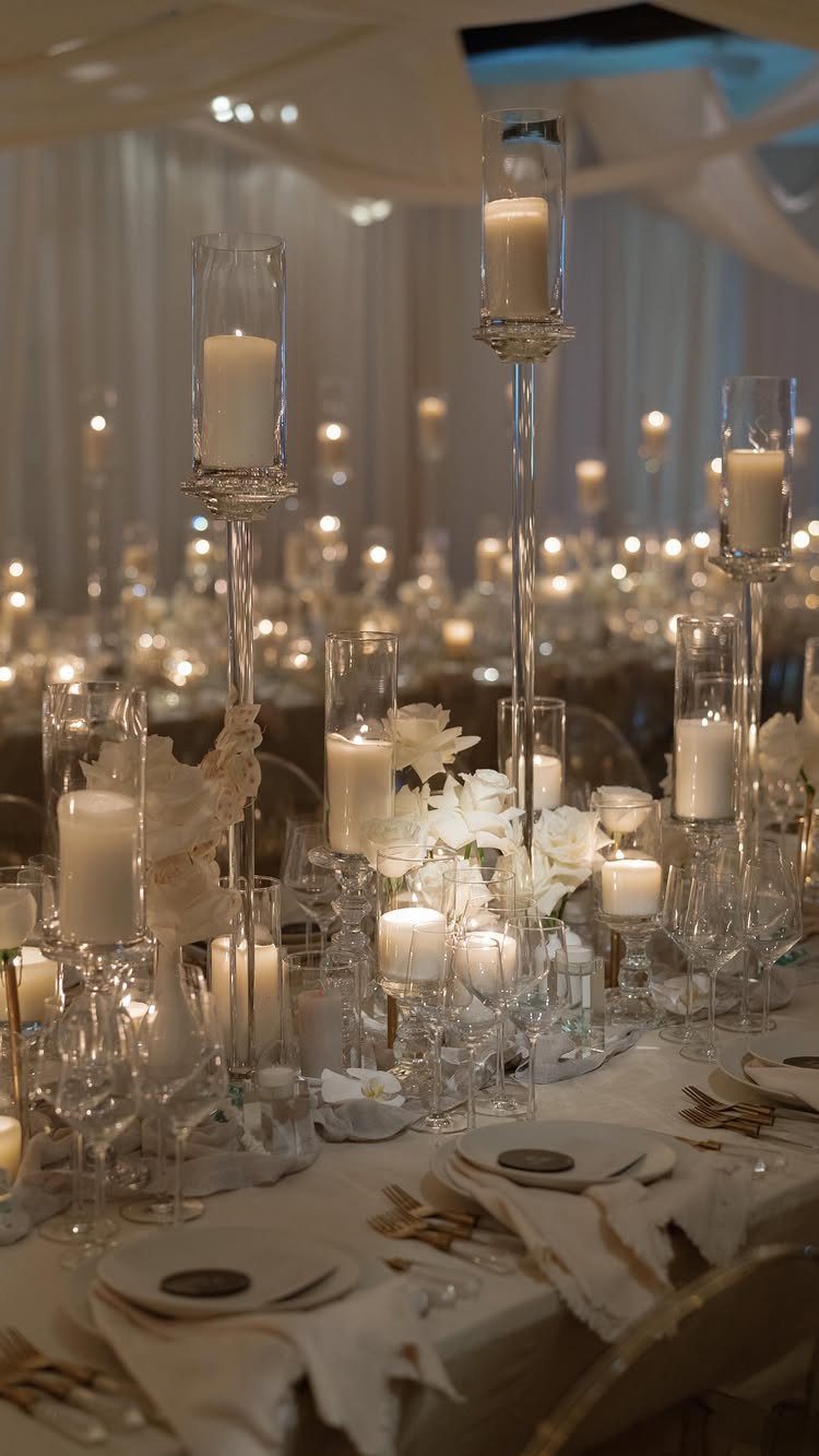 White Wedding Ideas: 23 Elegant Details for Your Big Day 10 White pillar candles in glass cylinders and white flowers on a wedding table.