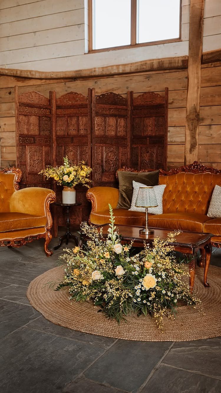 Cozy lounge area with leather furniture, yellow flowers, and rustic wooden walls.
