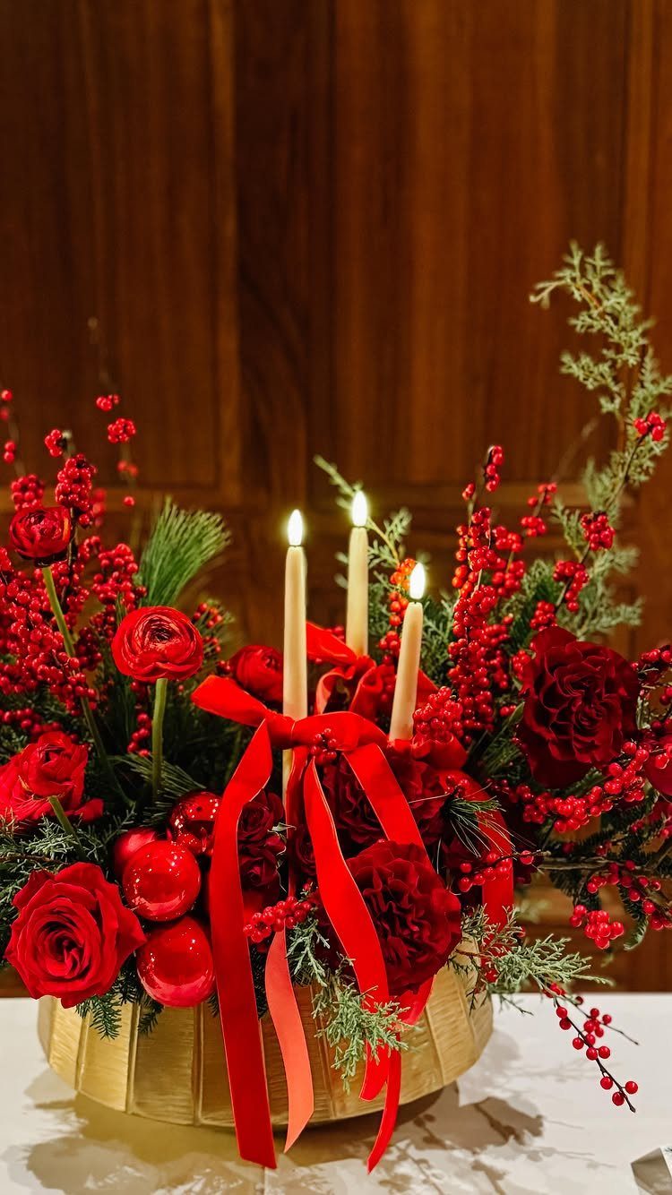 Red roses and berries with lit candles in a gold bowl centerpiece